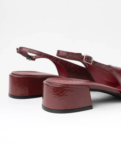 Escarpin slingback pour femme en cuir verni bordeaux lisse certifié LWG, avec bout rond légèrement structuré, talon bloc bas et stable d’environ 3,5 cm, et bride arrière réglable avec boucle métallique. Un modèle élégant, confortable et durable, parfait pour un usage quotidien ou professionnel.